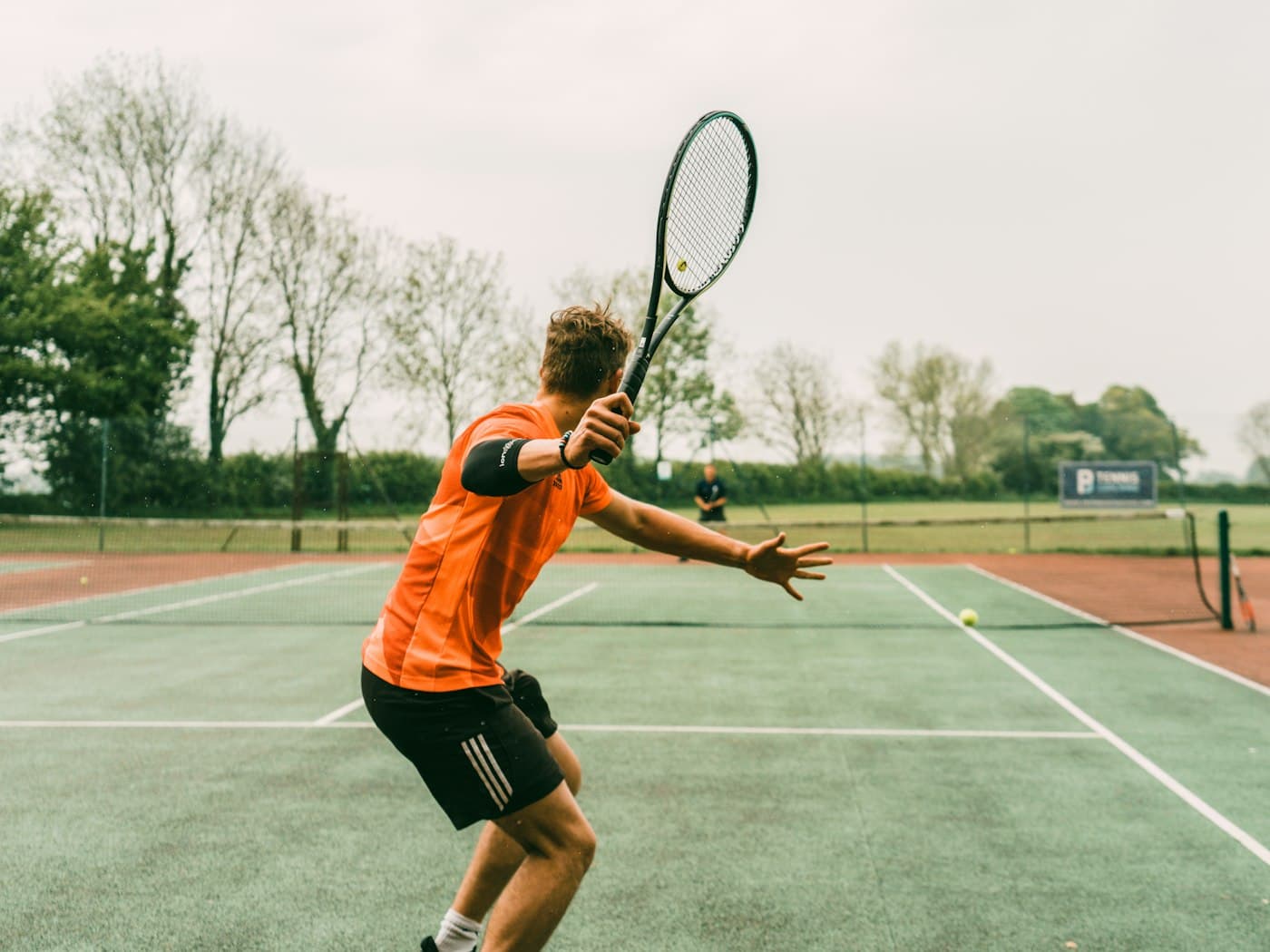A tennis player swinging at a ball on an outdoor court